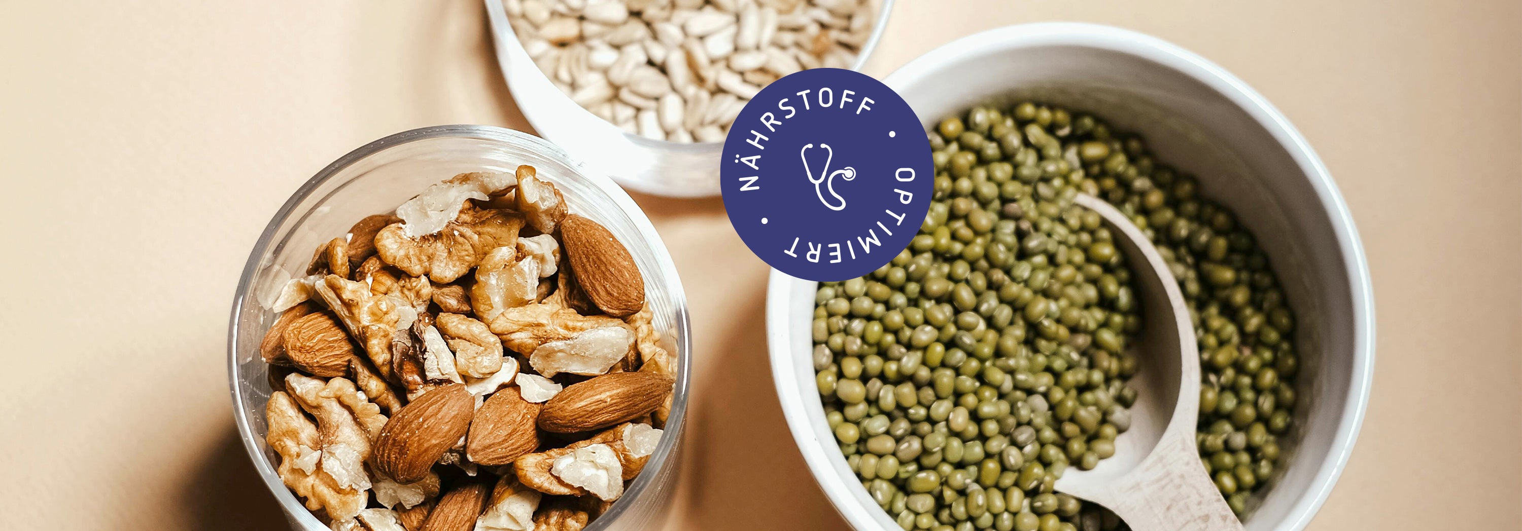 Drei Schalen mit Hülsenfrüchten, Nüssen und Kernen symbolisieren nährstoffreiche, gesunde Lebensmittel.